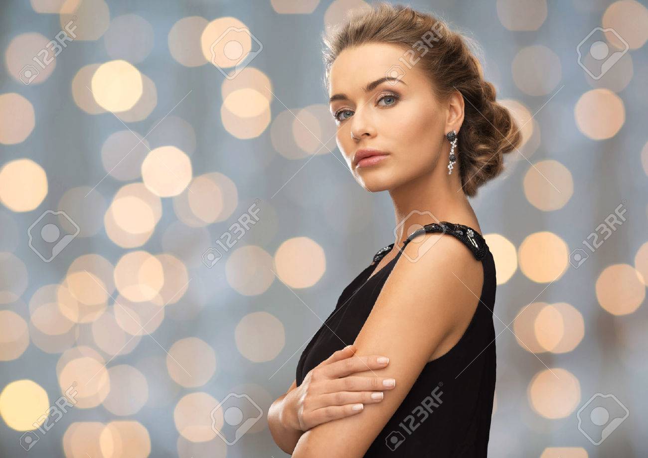 people, holidays and glamour concept - beautiful woman wearing earrings over lights background - 50589491 people, holidays and glamour concept - beautiful woman wearing earrings over lights background - 50589491