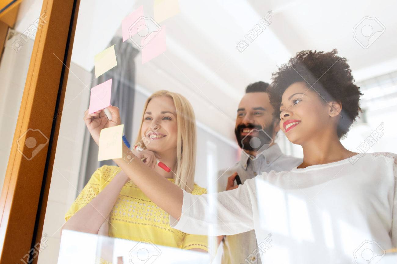happy international creative team writing on stickers at office glass board - 51808904 happy international creative team writing on stickers at office glass board - 51808904