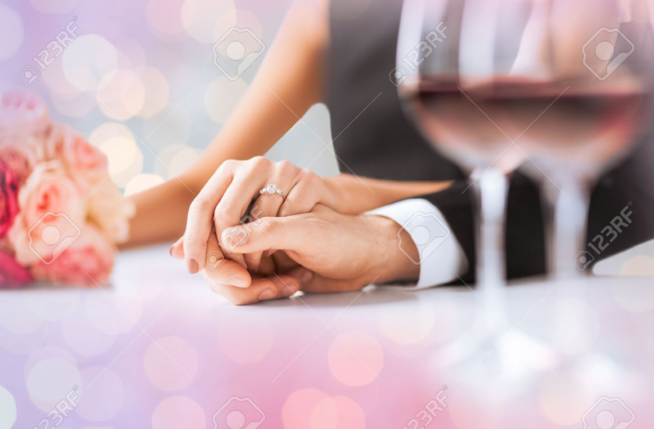 people, holidays, engagement and love concept - engaged couple holding hands with diamond ring over holidays lights background - 52118380 people, holidays, engagement and love concept - engaged couple holding hands with diamond ring over holidays lights background - 52118380