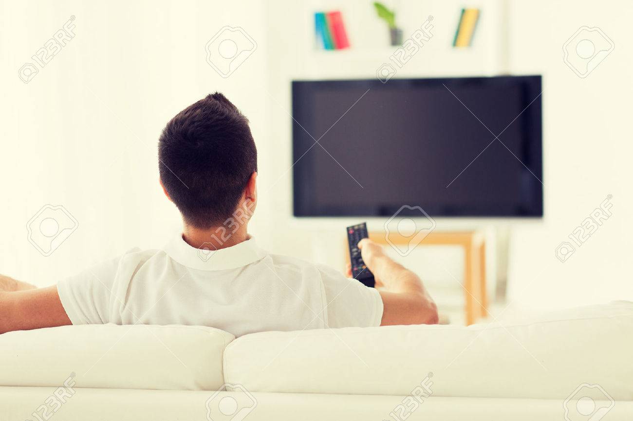 leisure, technology, mass media and people concept - man watching tv and changing channels at home from back - 52912878 leisure, technology, mass media and people concept - man watching tv and changing channels at home from back - 52912878