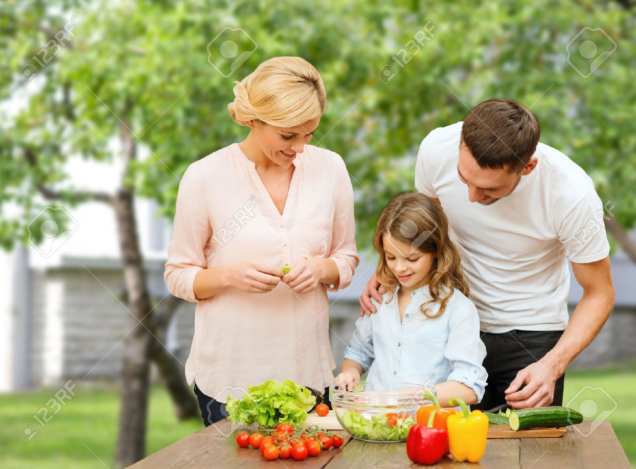 vegetarian food, culinary, happiness and people concept - happy family cooking vegetable salad for dinner over house and summer garden background - 54400016 vegetarian food, culinary, happiness and people concept - happy family cooking vegetable salad for dinner over house and summer garden background - 54400016