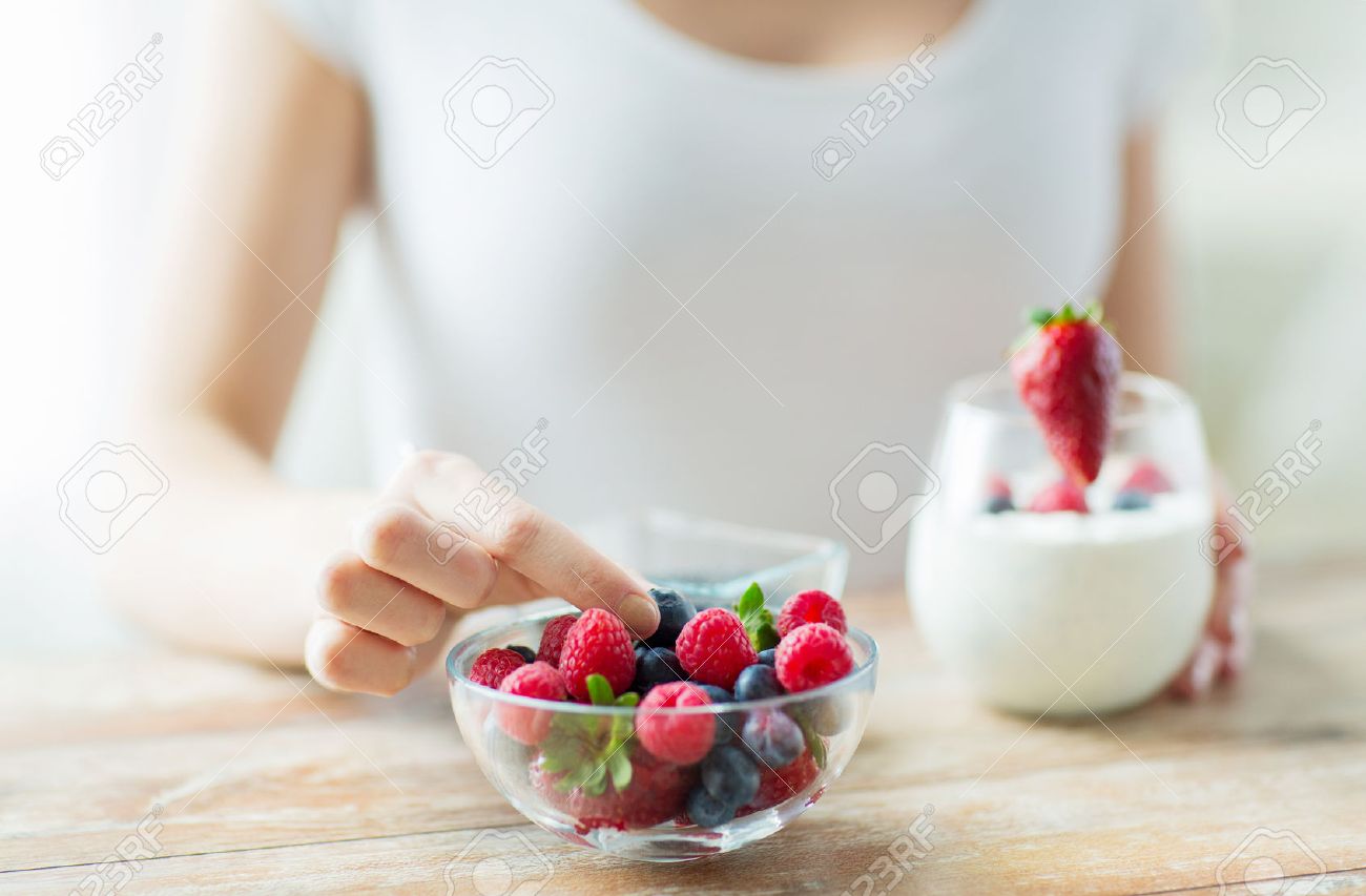 healthy eating, vegetarian food, diet and people concept - close up of woman hands with yogurt and berries on table - 54751589 healthy eating, vegetarian food, diet and people concept - close up of woman hands with yogurt and berries on table - 54751589