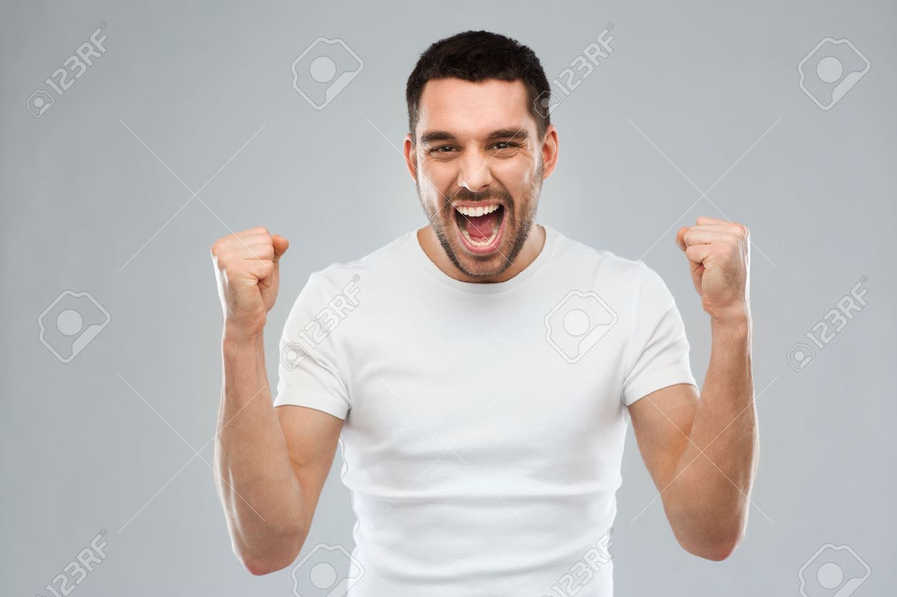emotion, success, gesture and people concept - young man celebrating victory over gray background - 54859663 emotion, success, gesture and people concept - young man celebrating victory over gray background - 54859663