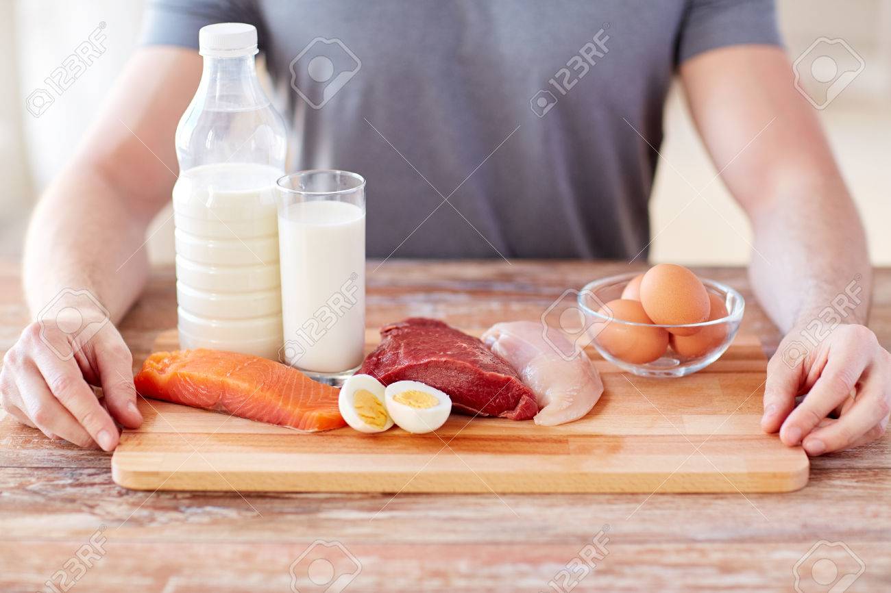 sport, fitness, healthy lifestyle, diet and people concept - close up of male hands with food rich in protein on cutting board on table - 57373647 sport, fitness, healthy lifestyle, diet and people concept - close up of male hands with food rich in protein on cutting board on table - 57373647