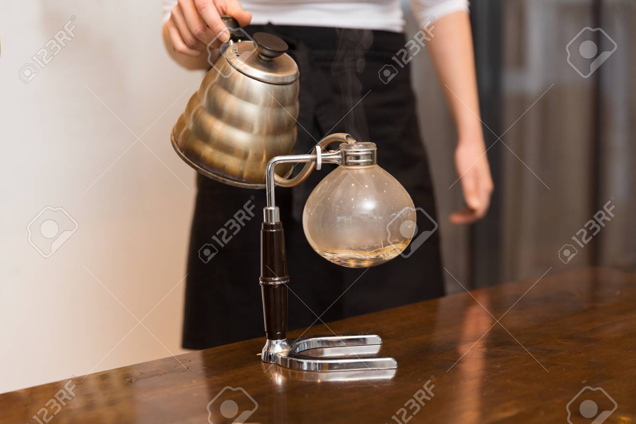 Equipos, cafetería, la gente y la tecnología concepto cerca de la mujer con el crisol de verter agua caliente para Chemex filtro de la cafetera en Equipos, cafetería, la gente y la tecnología concepto cerca de la mujer con el crisol de verter agua caliente para Chemex filtro de la cafetera en