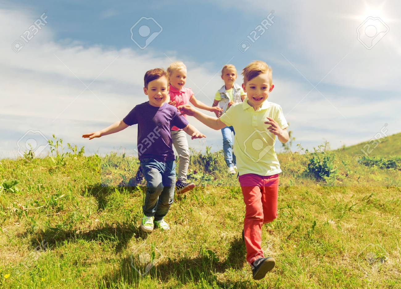 summer, childhood, leisure and people concept - group of happy kids playing tag game and running on green field outdoors - 63064321 summer, childhood, leisure and people concept - group of happy kids playing tag game and running on green field outdoors - 63064321