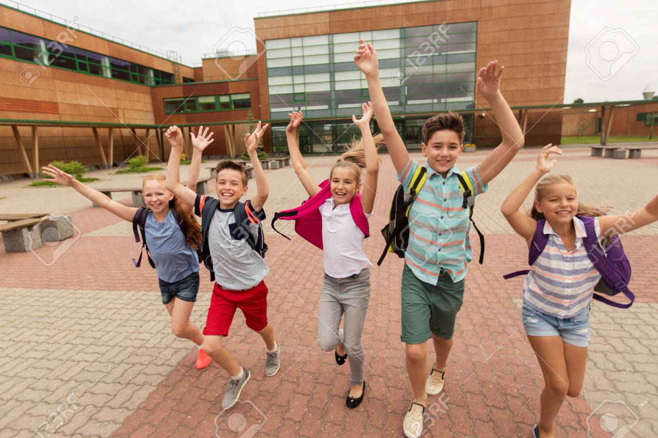 primary education, friendship, childhood and people concept - group of happy elementary school students with backpacks running and waving hands outdoors - 64634378 primary education, friendship, childhood and people concept - group of happy elementary school students with backpacks running and waving hands outdoors - 64634378