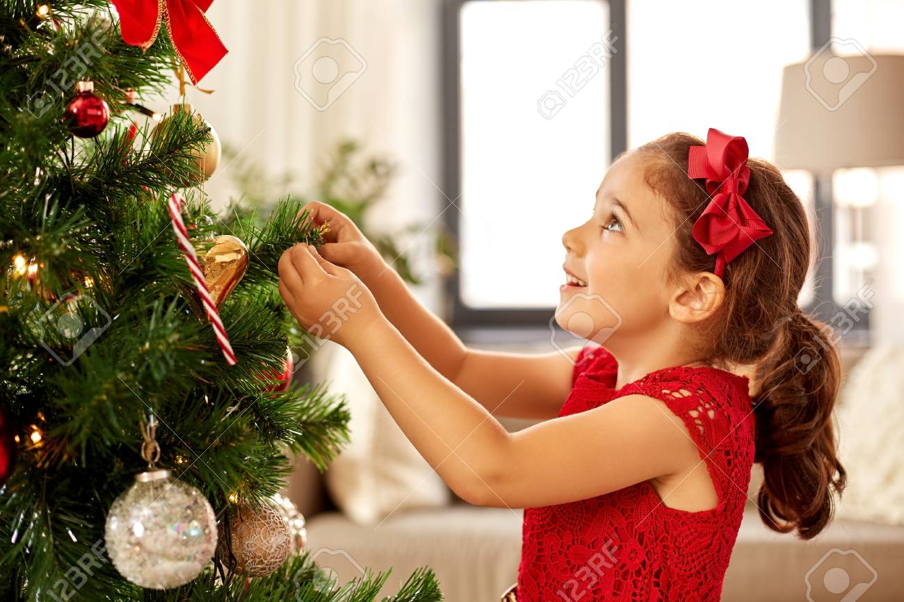 little girl decorating christmas tree at home - 108541753 little girl decorating christmas tree at home - 108541753