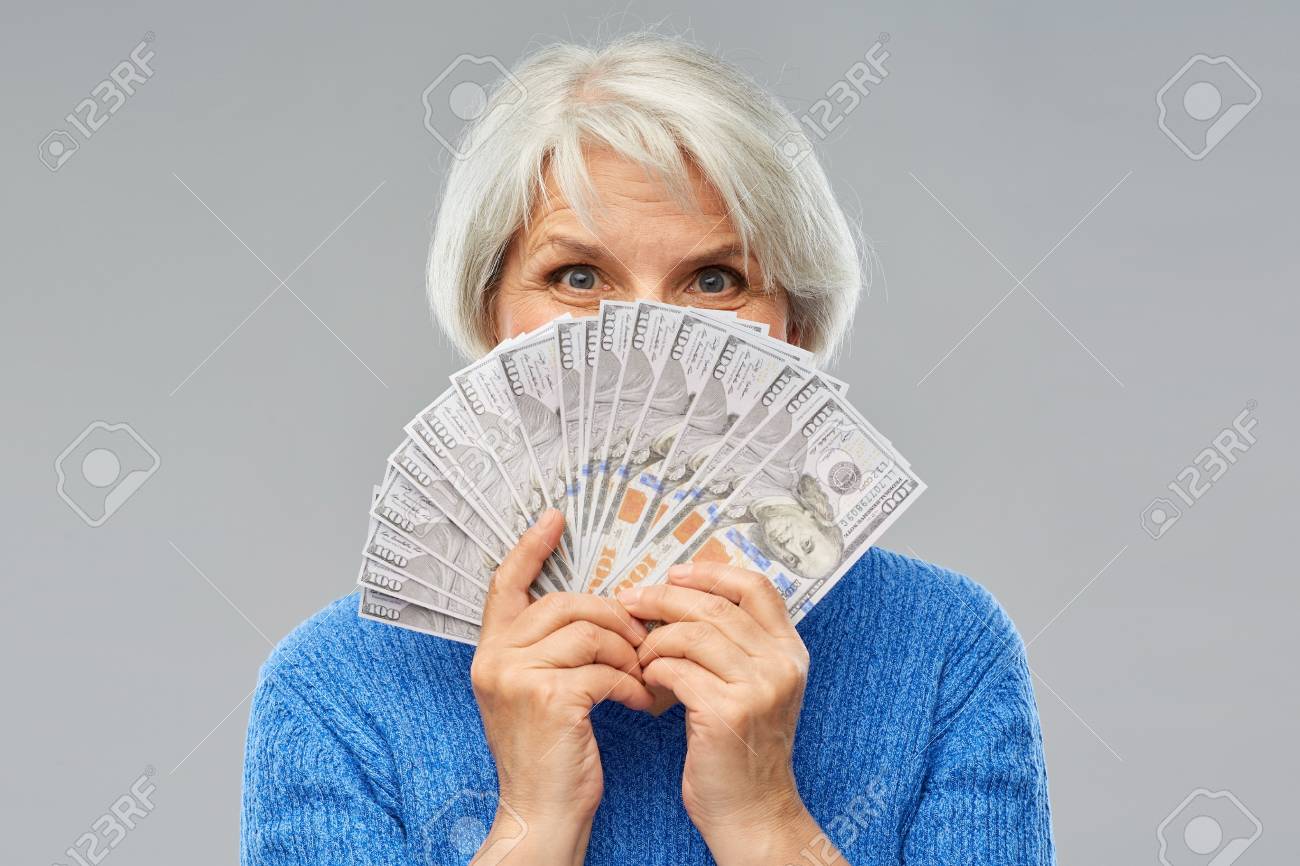 savings, finances and people concept - smiling senior woman hiding face behind hundreds of dollar money banknotes - 122616763 savings, finances and people concept - smiling senior woman hiding face behind hundreds of dollar money banknotes - 122616763