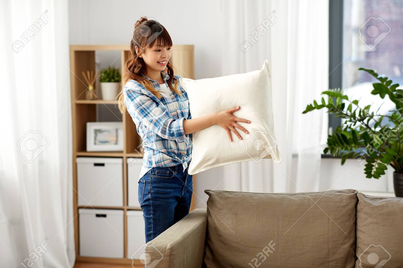 asian woman arranging sofa cushions at home - 123229512 asian woman arranging sofa cushions at home - 123229512