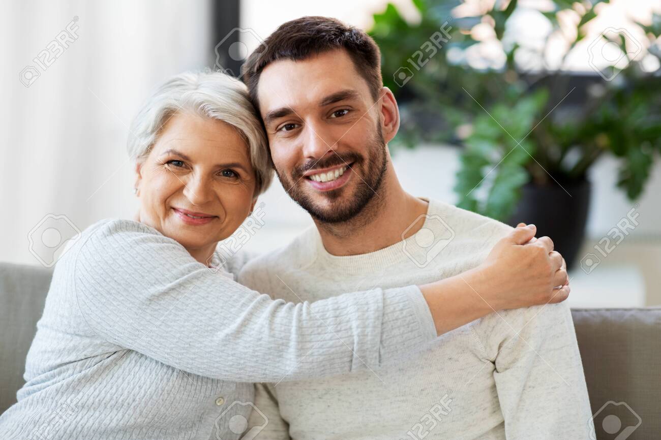 Senior mother with adult son hugging at home - 124940592 Senior mother with adult son hugging at home - 124940592