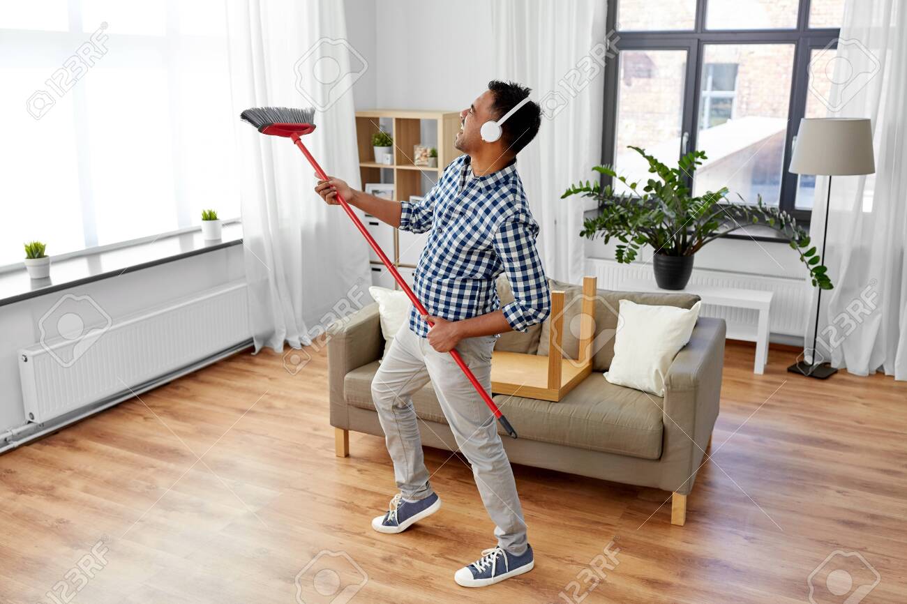Man with broom cleaning and having fun at home - 126163042 Man with broom cleaning and having fun at home - 126163042