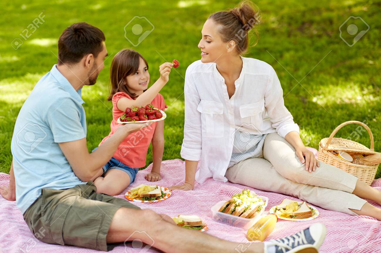 Family eating strawberries on picnic at park - 126941220 Family eating strawberries on picnic at park - 126941220