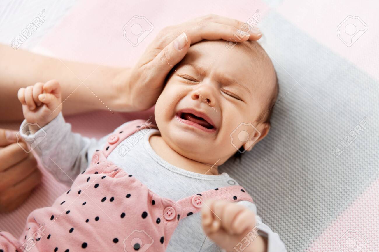 mothers hand touching crying little baby daughter - 127050756 mothers hand touching crying little baby daughter - 127050756