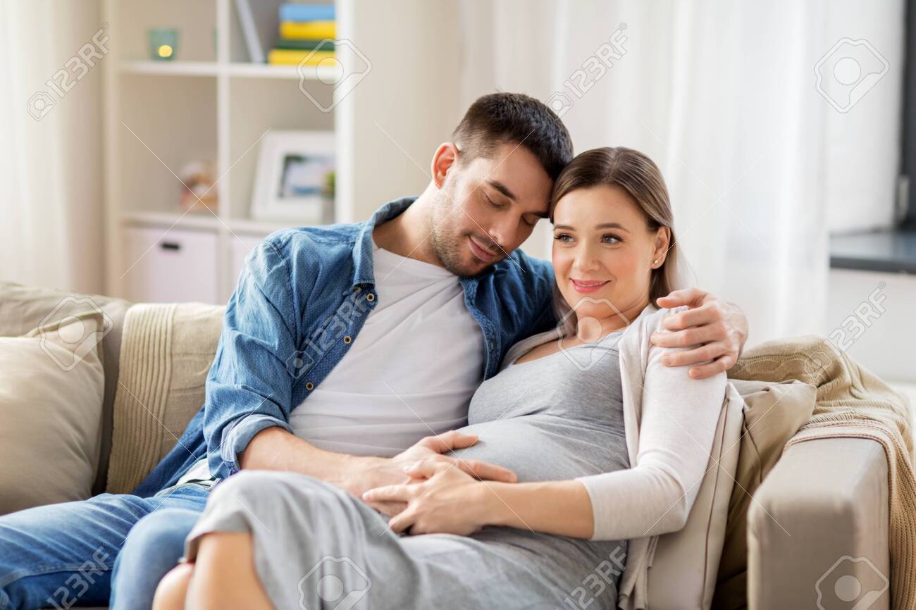 man hugging pregnant woman at home - 128850949 man hugging pregnant woman at home - 128850949