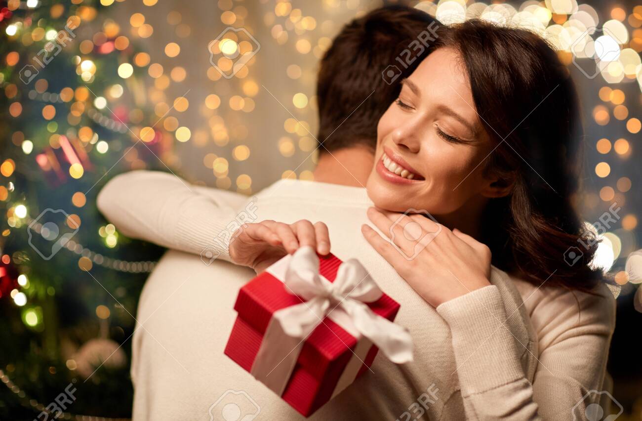 happy couple with christmas gift hugging at home - 131718762 happy couple with christmas gift hugging at home - 131718762