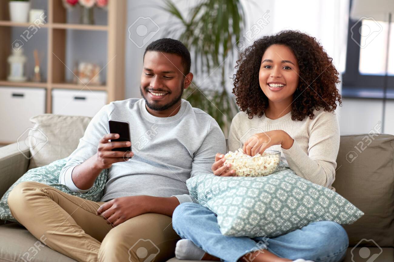 african couple with popcorn watching tv at home - 133888330 african couple with popcorn watching tv at home - 133888330