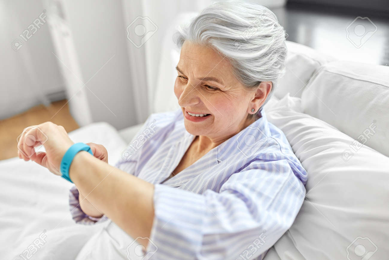 happy old woman with health tracker sitting in bed - 169967654 happy old woman with health tracker sitting in bed - 169967654