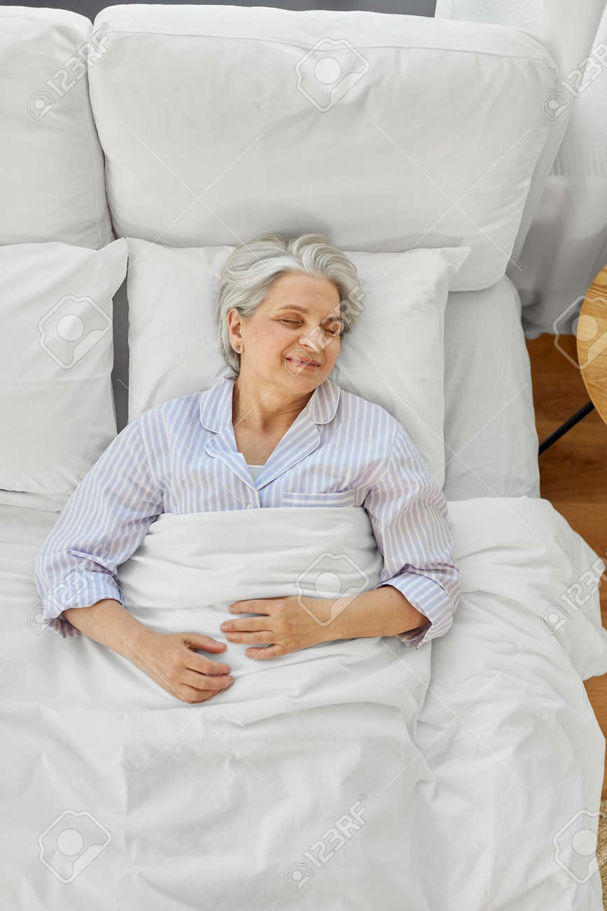 happy senior woman sleeping in bed at home bedroom - 169967556 happy senior woman sleeping in bed at home bedroom - 169967556