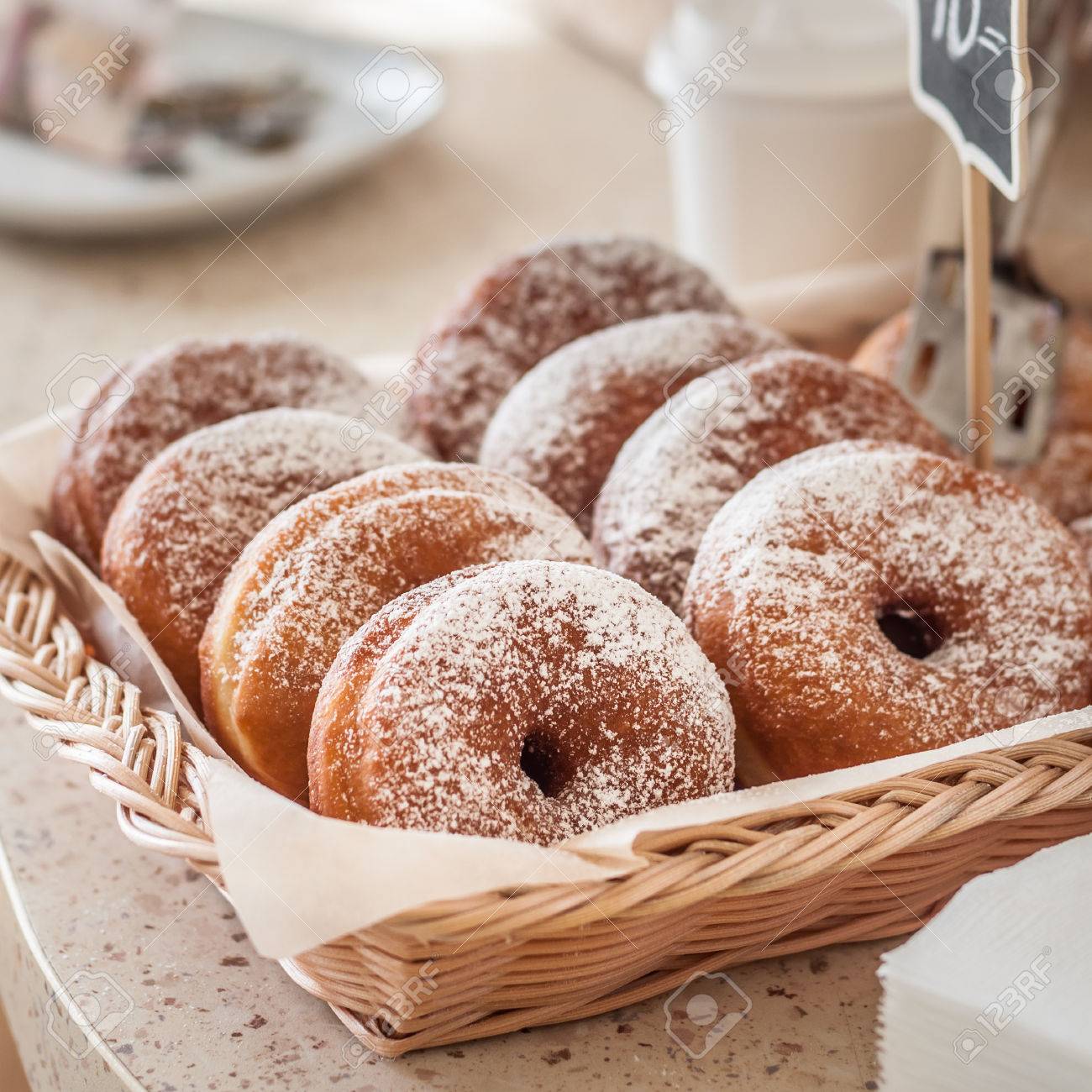 doughnut store counter donuts with icing sugar in a display stock
