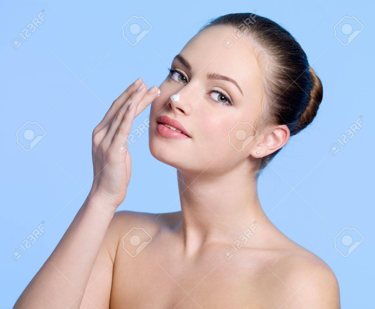 美しいセクシーな若い女の子の彼女の鼻 青い背景にクリームを適用します の写真素材 画像素材 Image