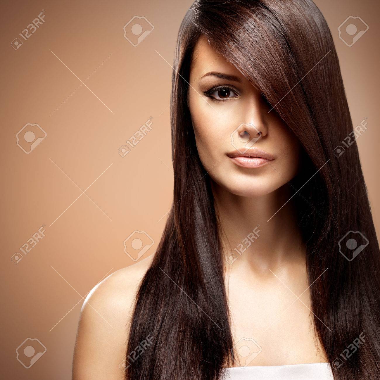 Beautiful young woman with long straight brown hair. Fashion model posing at studio over beige background - 63432208 Beautiful young woman with long straight brown hair. Fashion model posing at studio over beige background - 63432208