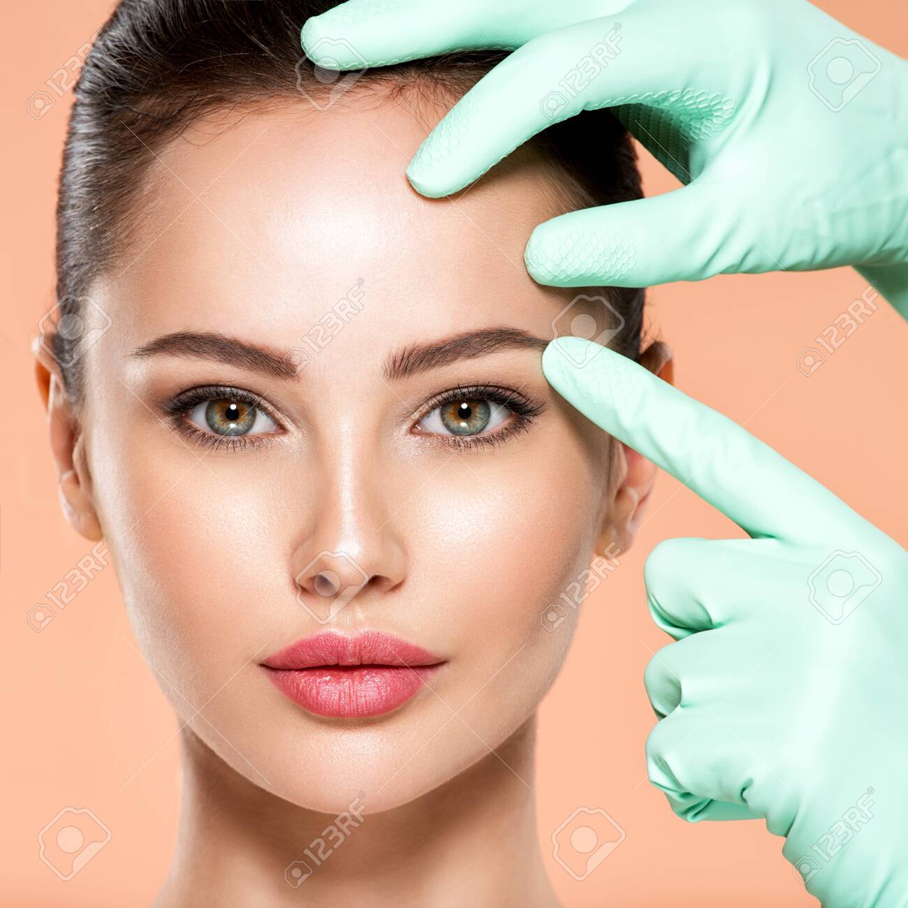 Face skin check before plastic surgery. Beautician touching young woman face. Doctor in medicine gloves checks a skin before plastic surgery. Beauty treatments. Colorful image - 155080021 Face skin check before plastic surgery. Beautician touching young woman face. Doctor in medicine gloves checks a skin before plastic surgery. Beauty treatments. Colorful image - 155080021