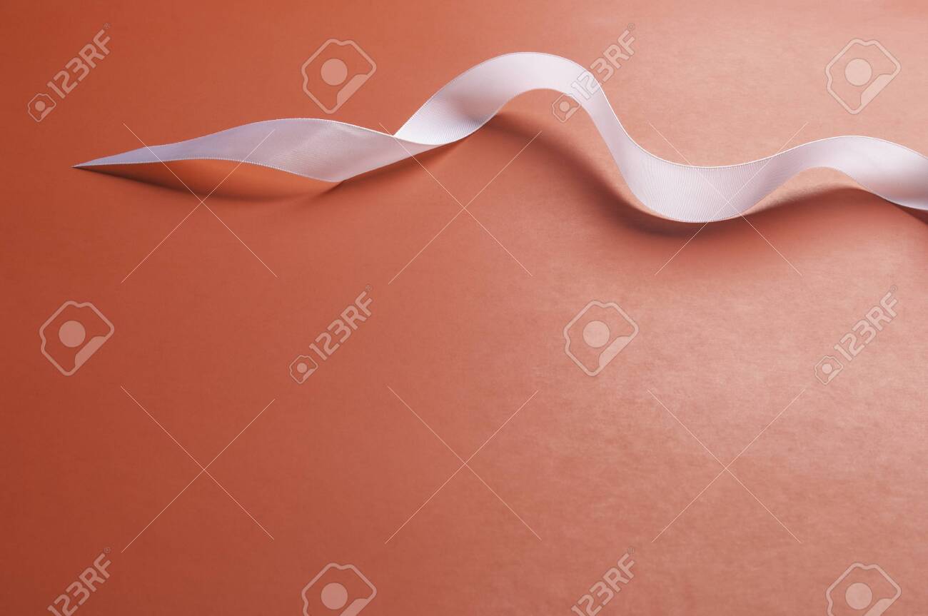 a swirl of white satin ribbon set on a plain red background in plain red background