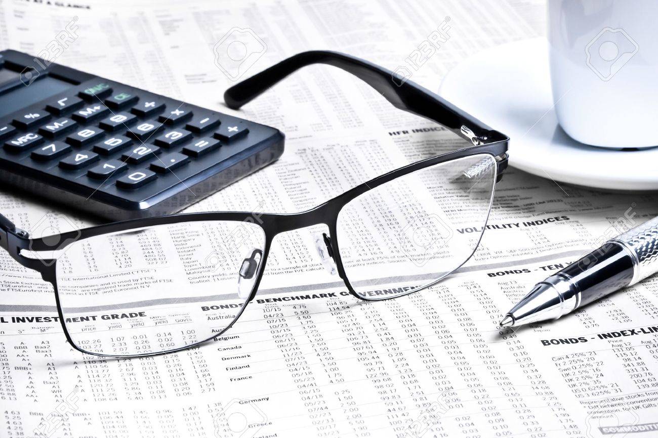 detail of a pen and glasses near a calculator with cup of coffee on financial newspaper - 22668222 detail of a pen and glasses near a calculator with cup of coffee on financial newspaper - 22668222
