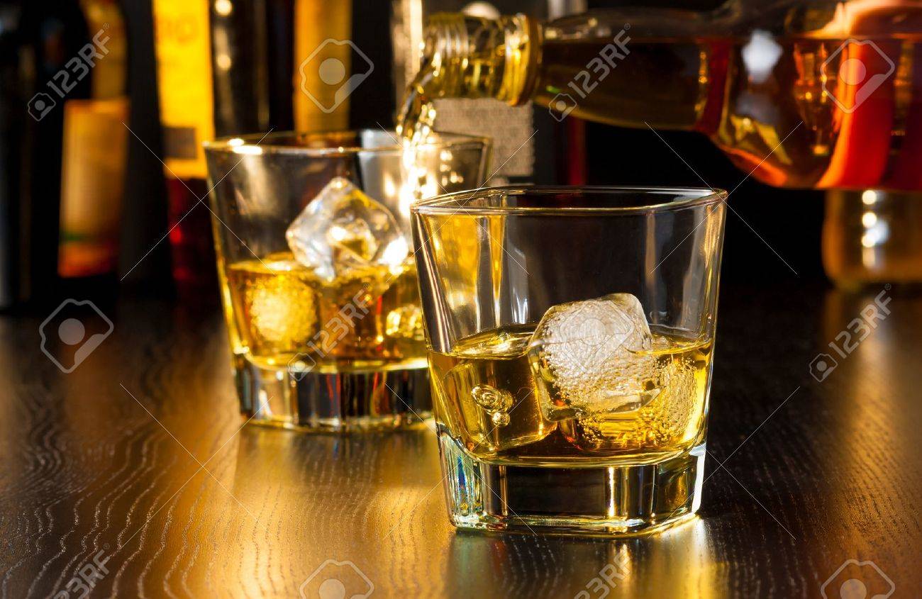 barman pouring whiskey behind whiskey glass on wood table - 28756581 barman pouring whiskey behind whiskey glass on wood table - 28756581