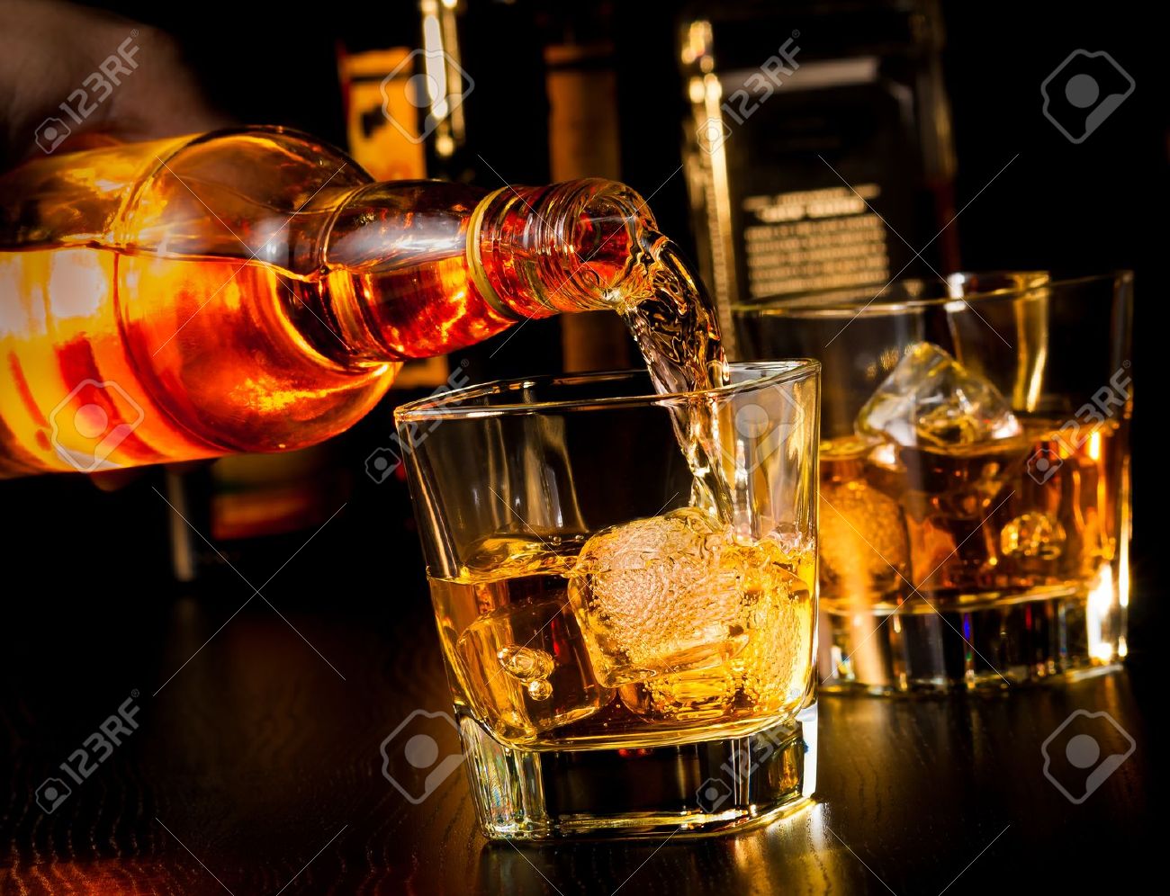 barman pouring whiskey in front of whiskey glass and bottles on wood table - 28755716 barman pouring whiskey in front of whiskey glass and bottles on wood table - 28755716