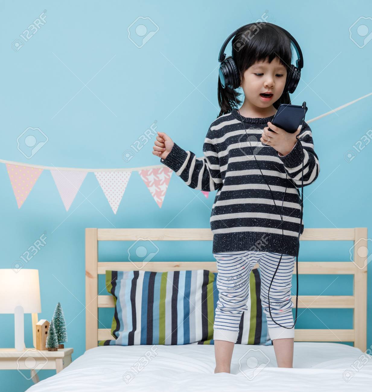 Cute Little Girl Sing A Song With Smartphone In Her Bedroom