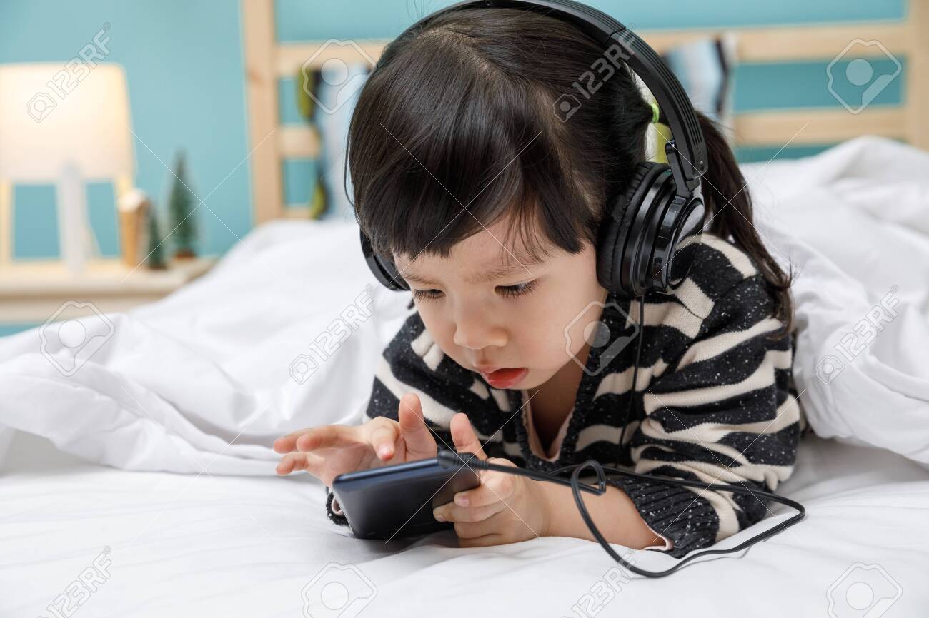 Cute Little Girl Sing A Song With Smartphone In Her Bedroom