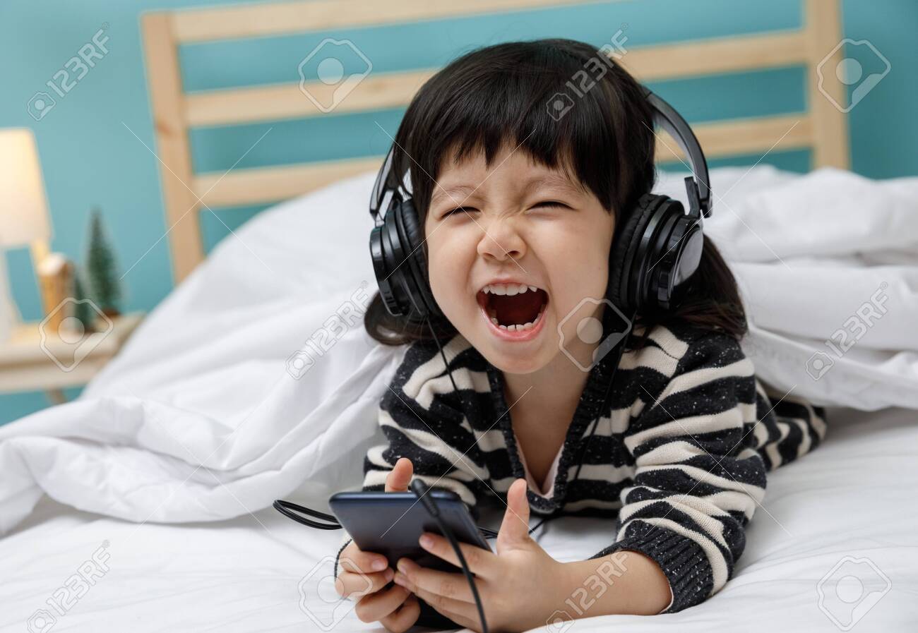 Cute Little Girl Sing A Song With Smartphone In Her Bedroom