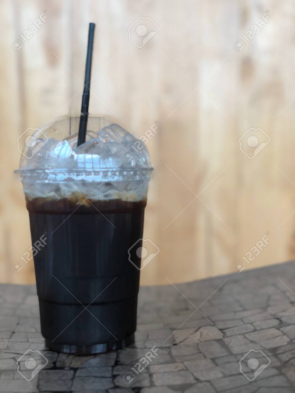 Iced black coffee or iced Americano with straw on wood table - 97967557 Iced black coffee or iced Americano with straw on wood table - 97967557