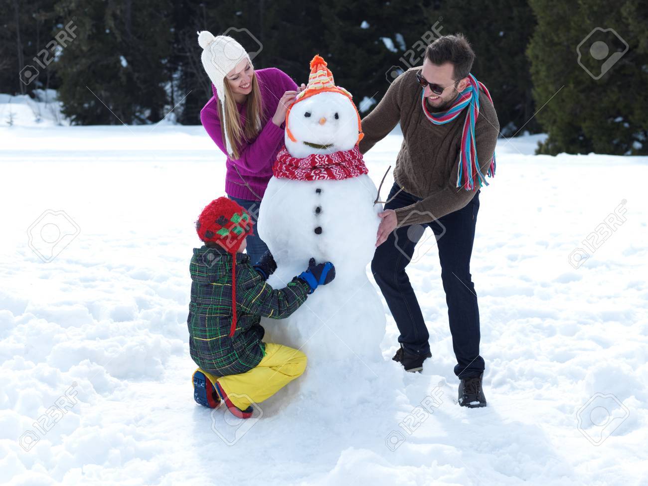 Joven Familia Feliz Jugando En La Nieve Fresca Y Haciendo Muñeco De Nieve En El Hermoso Día De Invierno Soleado Al Aire Libre En La Naturaleza Con El Bosque En Fondo Fotos