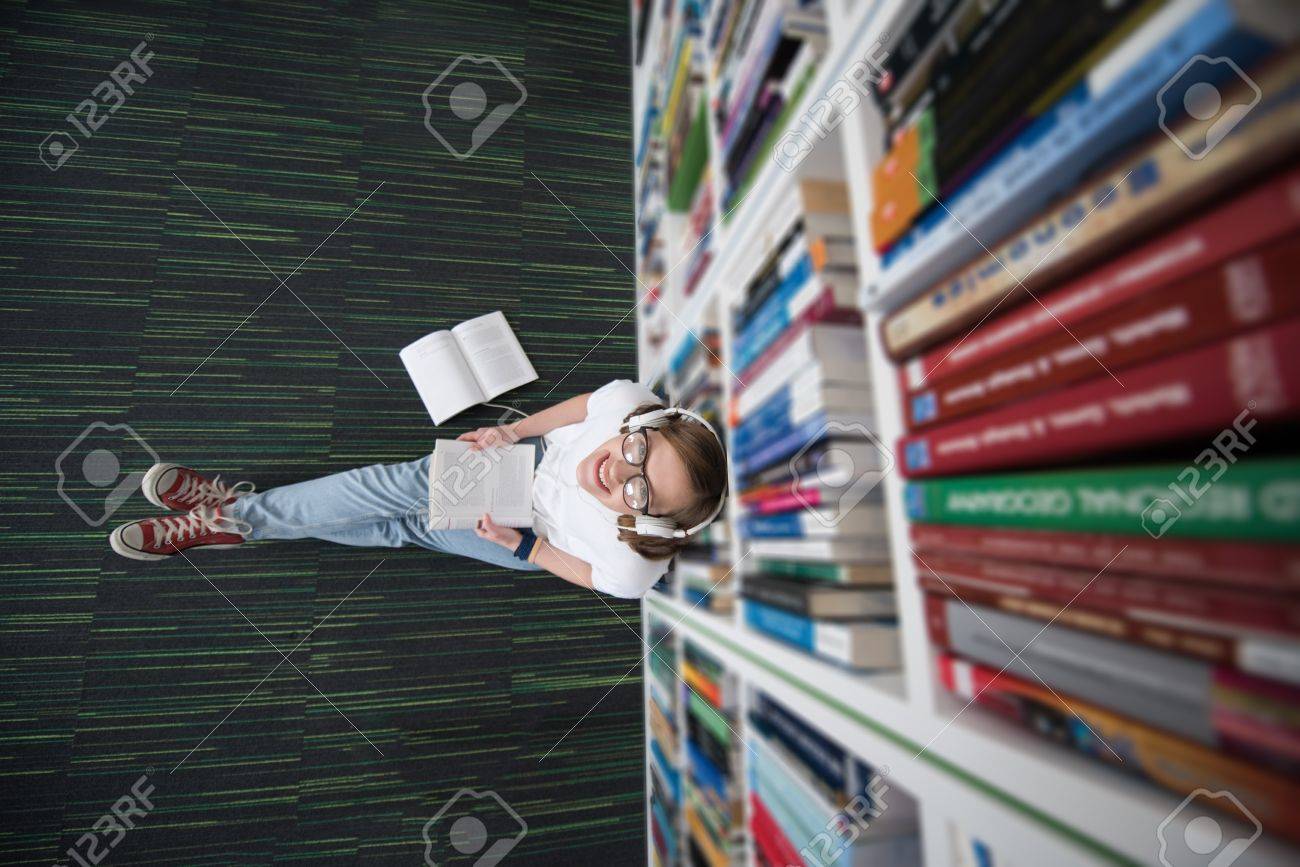 female student study in school library, using tablet and searching for information’s on internet. Listening music and lessons on white headphones - 57689154 female student study in school library, using tablet and searching for information’s on internet. Listening music and lessons on white headphones - 57689154