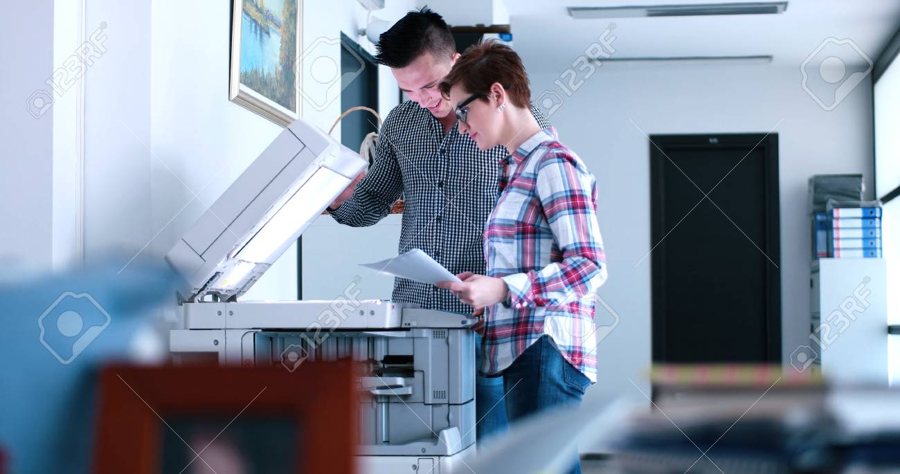 Young Beautiful Woman with assistant Making Copies Of Files In The Copy Machine - 76533225 Young Beautiful Woman with assistant Making Copies Of Files In The Copy Machine - 76533225