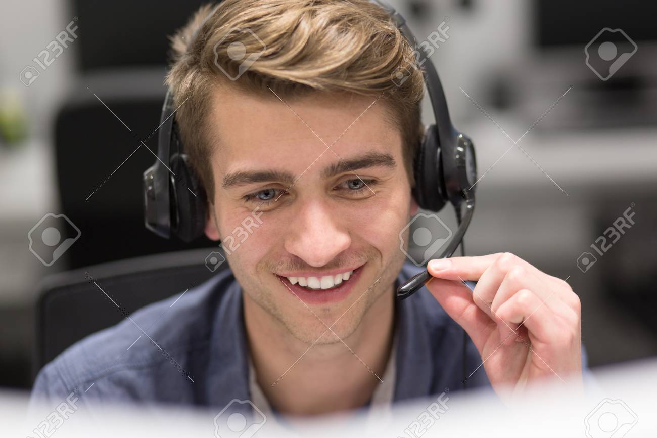 young smiling male call centre operator doing his job with a headset - 84851264 young smiling male call centre operator doing his job with a headset - 84851264
