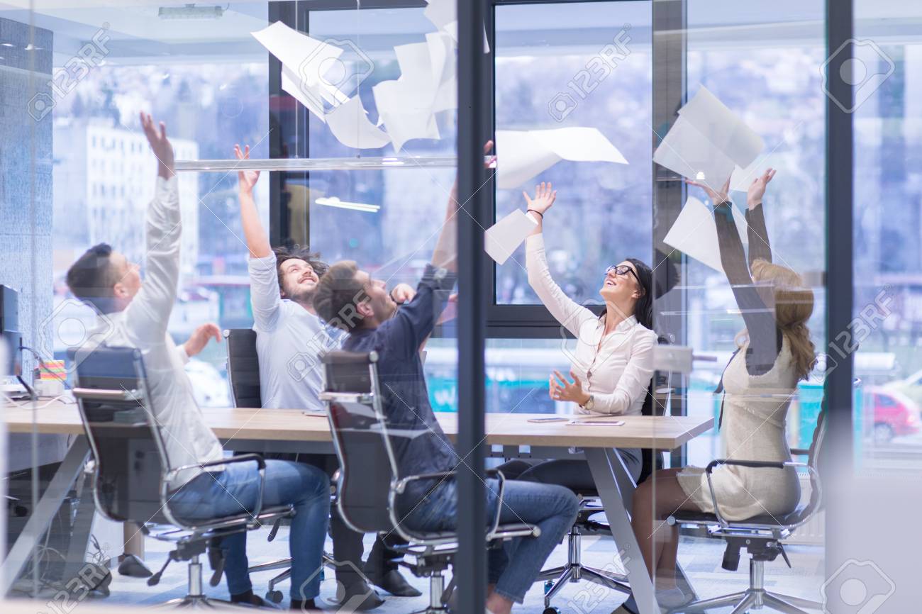 Group of young business people throwing documents and looking happy while celebrating success at their working places in startup office - 89477128 Group of young business people throwing documents and looking happy while celebrating success at their working places in startup office - 89477128