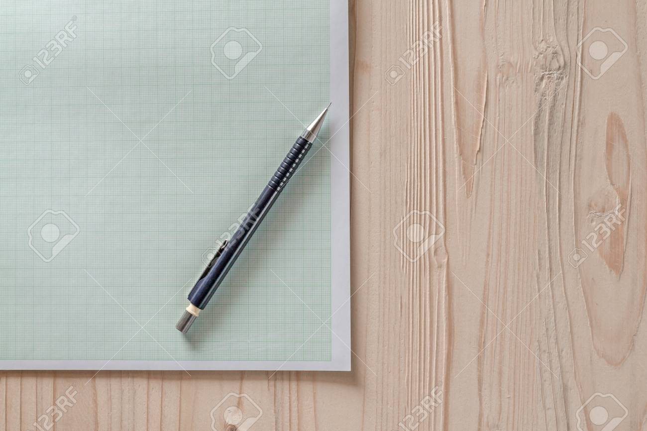 drafting paper or graph paper with pencil on wooden desk close
