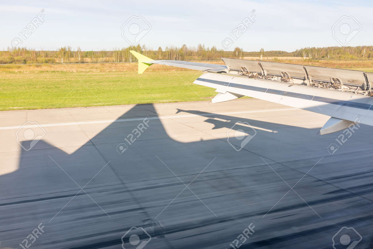 View of airplane wing, Shadow of the plane on the ground during landing, seen from the plane window. Earth and sky as seen through window of an airplane. - 170095176 View of airplane wing, Shadow of the plane on the ground during landing, seen from the plane window. Earth and sky as seen through window of an airplane. - 170095176