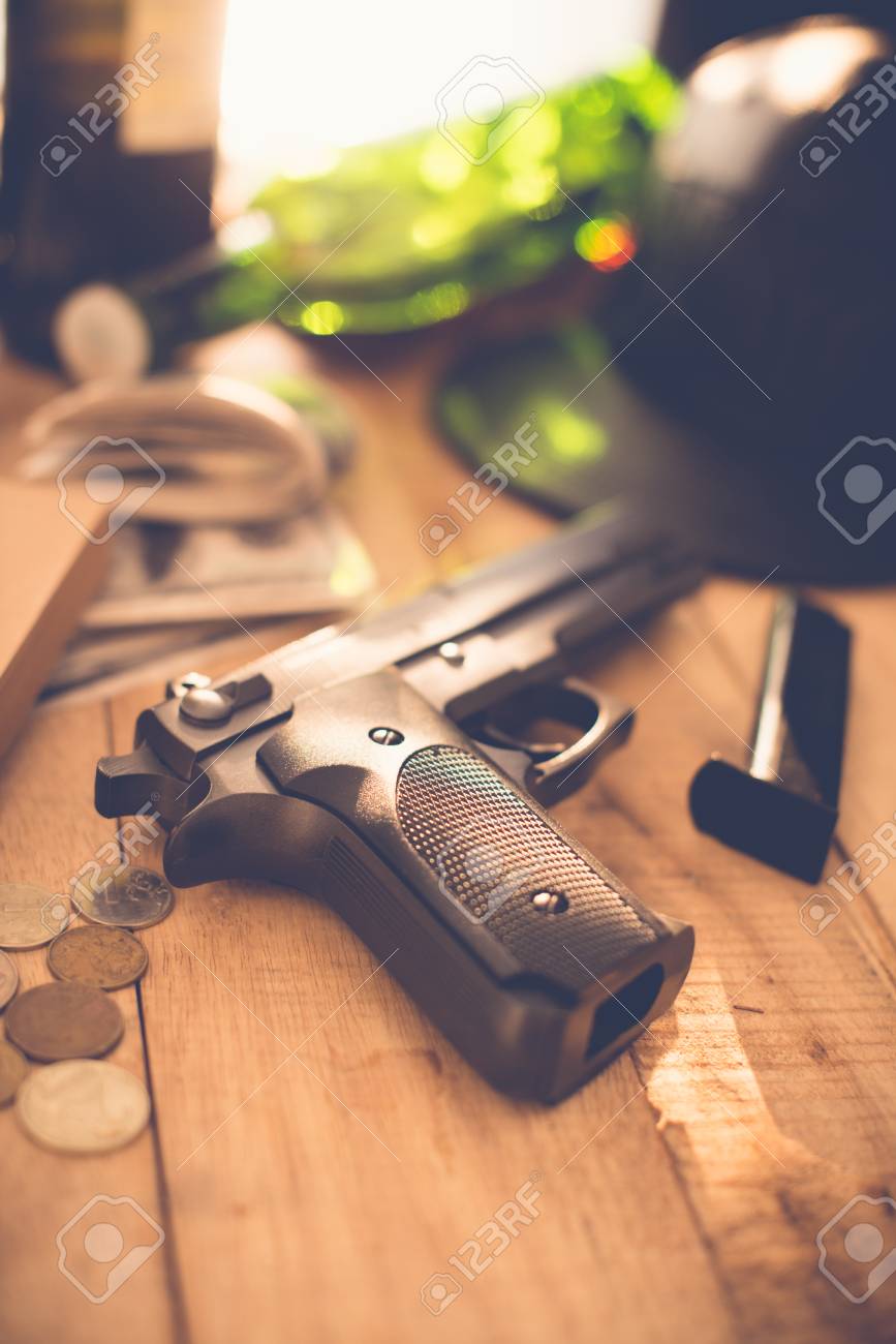 木製のテーブル上のコインが付いている銃の写真素材・画像素材 Image 76860347
