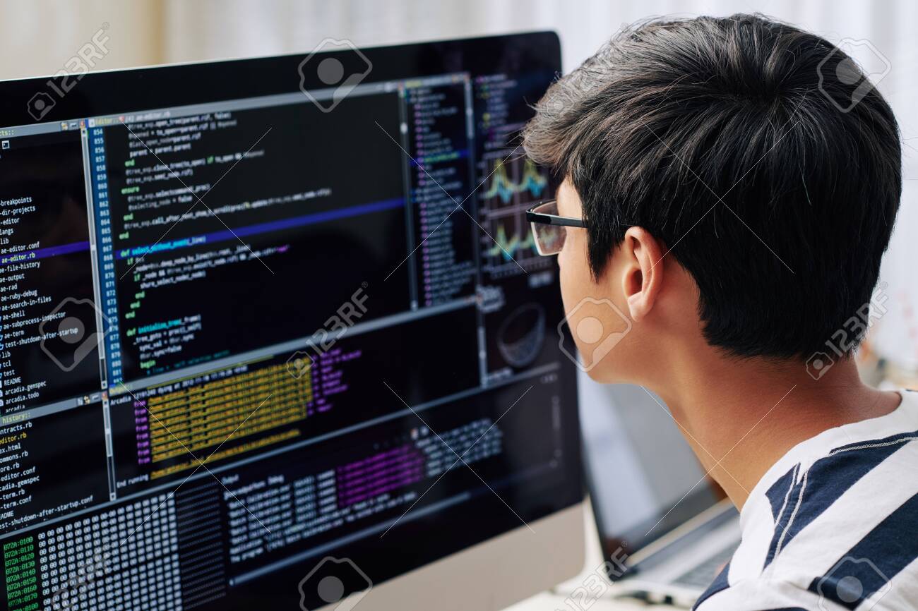 Smart teenage boy in glasses checking programming code on computer screen when sitting at his desk - 131720891 Smart teenage boy in glasses checking programming code on computer screen when sitting at his desk - 131720891
