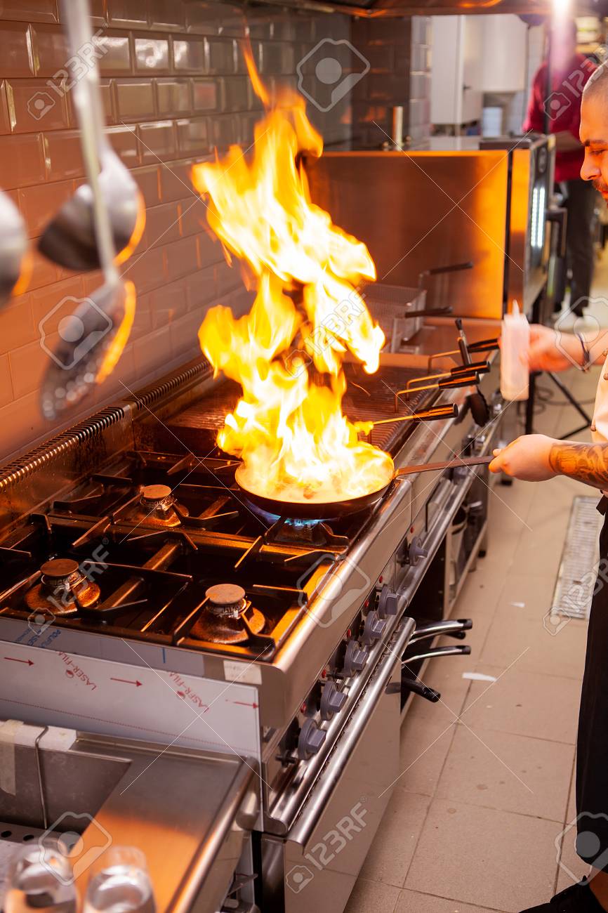 The Chef Prepares The Dish On The Stove With An Open Fire In Stock Photo Picture And Royalty Free Image Image 114224841