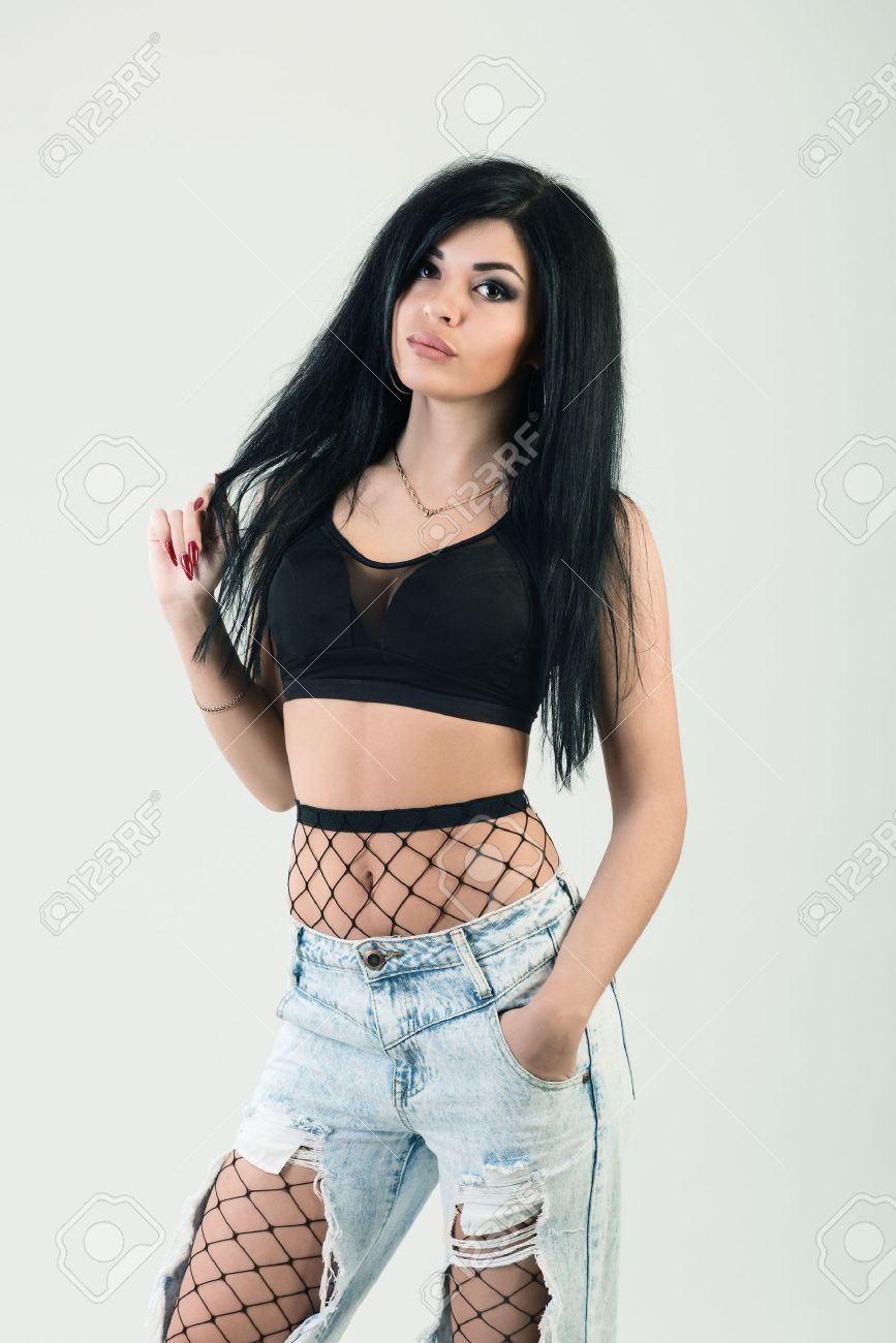 ポーズの若いスタイリッシュな流行に敏感な女の子 スタイリッシュな女性の一見 網タイツと黒のトップとトレンディなジーンズのクローズ アップ ファッション ポートレート の写真素材 画像素材 Image