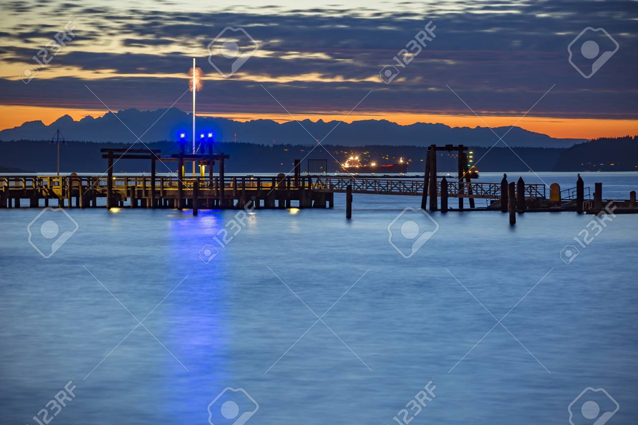 タコマはアメリカの国旗の日没の長時間露光でドッキングします 夕暮れ時と日暮れにワシントン州タコマの湾 の写真素材 画像素材 Image