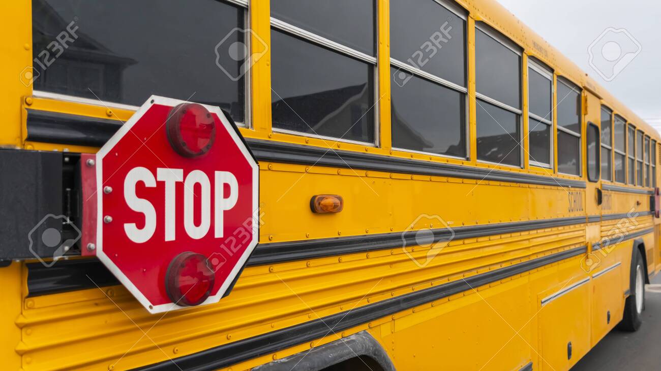 Panorama Exterior view of a yellow school bus with a red stop sign and signal lights. The glass windows reflects the homes and cloudy sky in the snowy neighborhood. - 122767446 Panorama Exterior view of a yellow school bus with a red stop sign and signal lights. The glass windows reflects the homes and cloudy sky in the snowy neighborhood. - 122767446