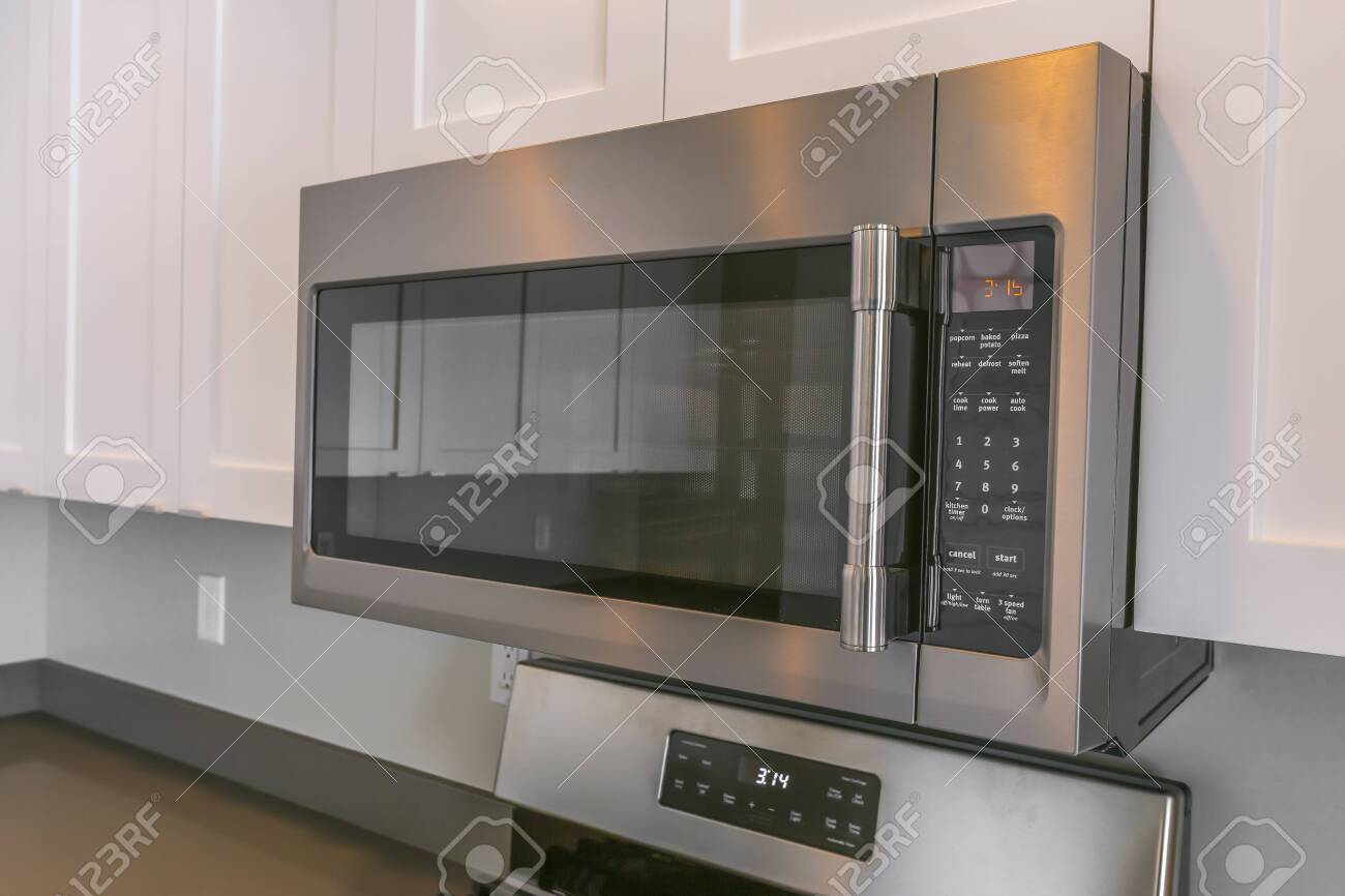 Close Up Of A Microwave And White Cabinets Mounted On The Wall