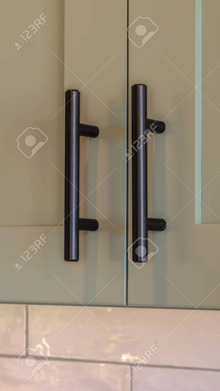 Vertical Frame Close Up Of Overhead Kitchen Cupboard Handles Stock Photo